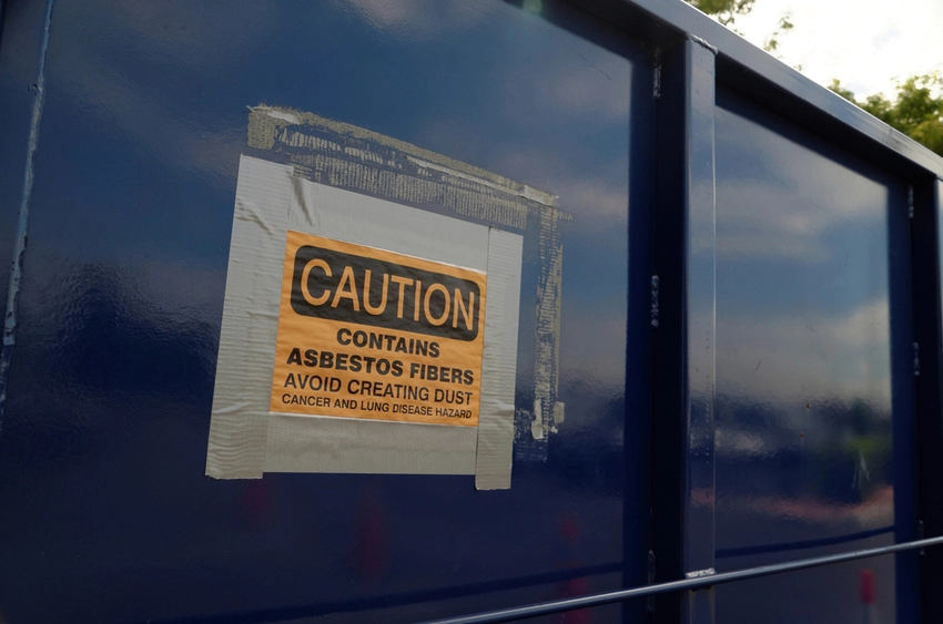 Container labeled with asbestos warning during residential asbestos removal project
