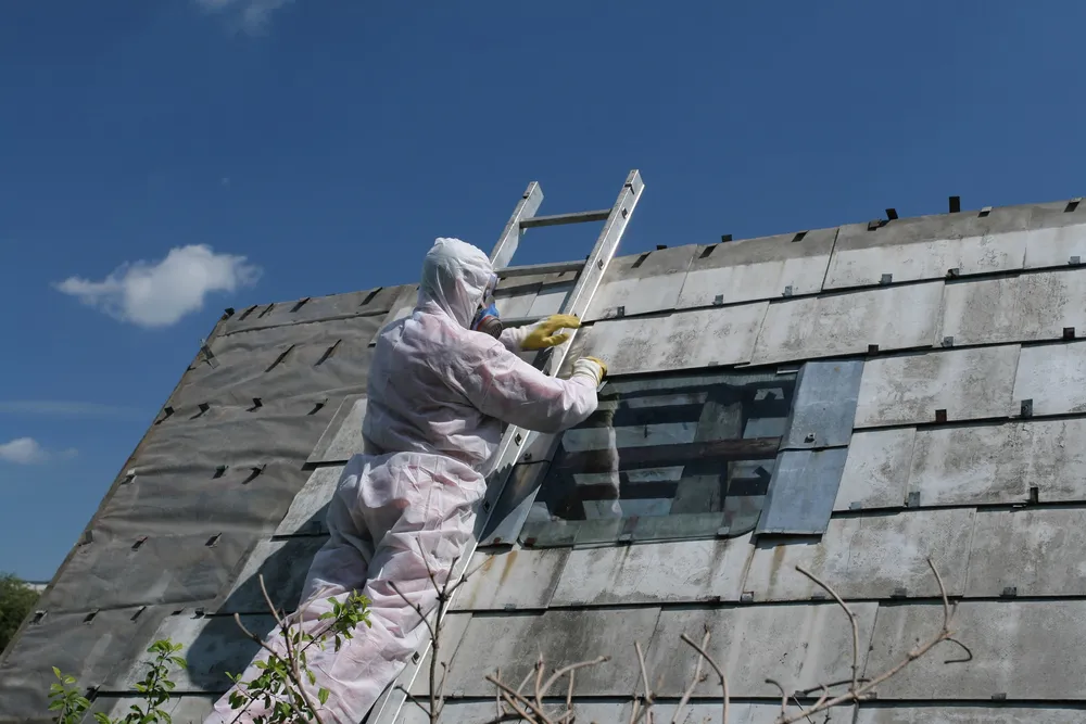 Man on ladder professionally removing asbestos for Rhode Island home