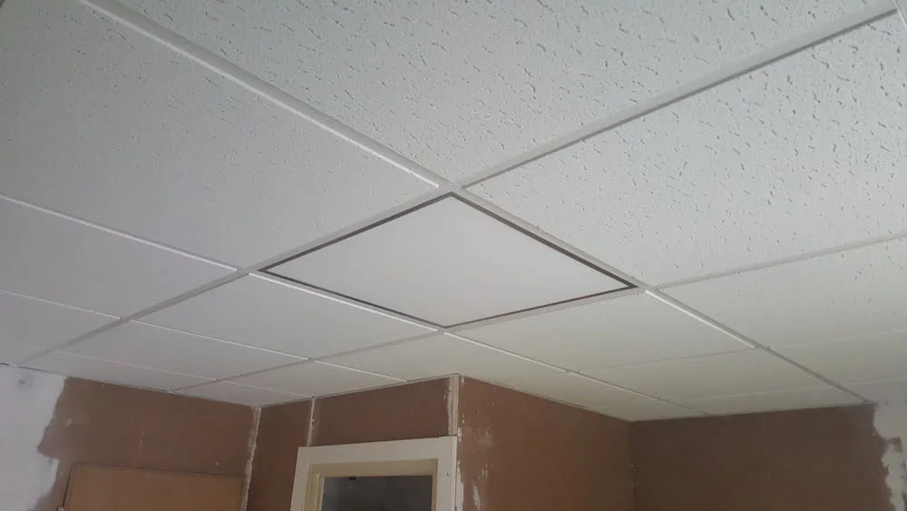 White textured ceiling tiles in a suspended grid above unfinished walls